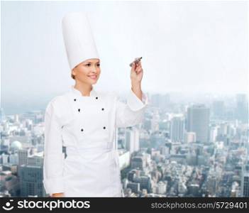 people, cooking and advertisement concept - smiling female chef, cook or baker with marker writing something on air over city background