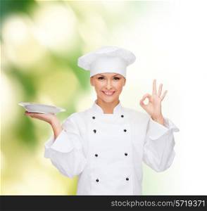 people, cooking and food concept - smiling female chef, cook or baker with plate showing ok sign over green background