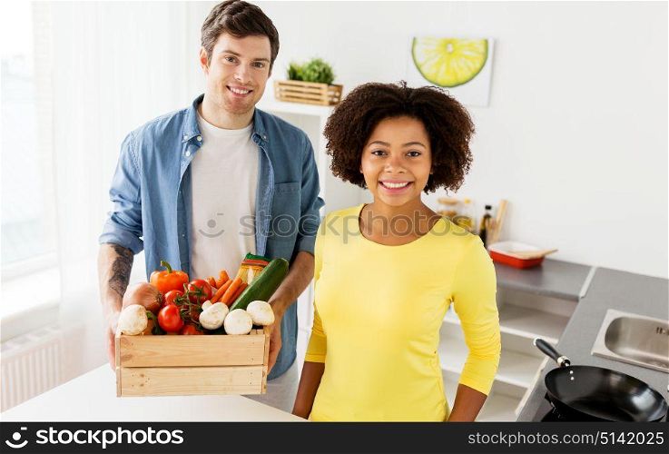 people, cooking and healthy eating concept - happy couple with box of food at home kitchen. happy couple with healthy food at home kitchen