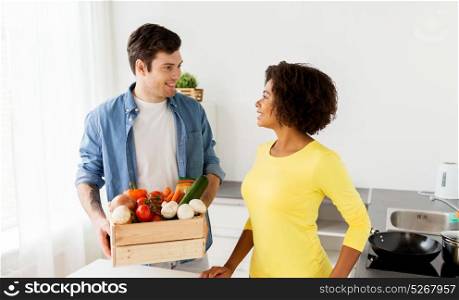 people, cooking and healthy eating concept - happy couple with box of food at home kitchen. happy couple with healthy food at home kitchen