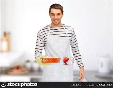 people, cooking, culinary and food concept - happy man or cook in apron with baking and kitchenware over home kitchen background