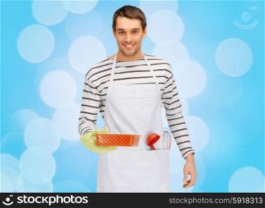 people, cooking, culinary and food concept - happy man or cook in apron with baking and kitchenware over blue lights background