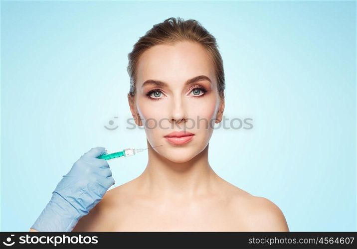 people, cosmetology, plastic surgery and beauty concept - beautiful young woman face and beautician hand in glove with syringe making injection over blue background