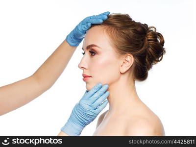 people, cosmetology, plastic surgery and beauty concept - surgeon or beautician hands touching woman face over white background