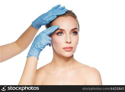 people, cosmetology, plastic surgery and beauty concept - surgeon or beautician hands touching woman face over white background