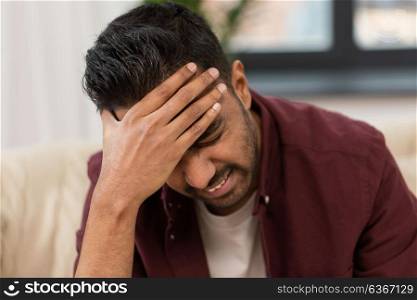people, crisis, emotions and stress concept - close up of man suffering from head ache at home. close up of man suffering from head ache at home