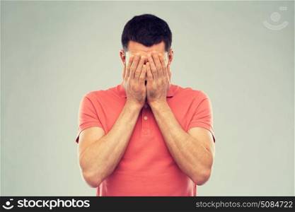 people, crisis, emotions and stress concept - man in t-shirt covering his face with hands over gray background. man in t-shirt covering his face with hands. man in t-shirt covering his face with hands