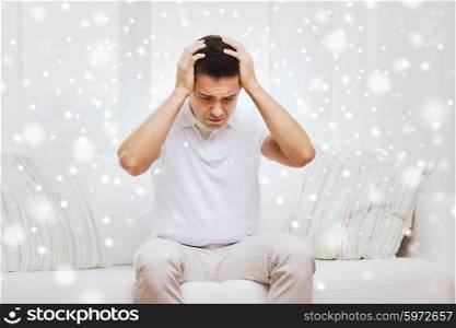 people, crisis, emotions and stress concept - unhappy man suffering from head ache at home over snow effect