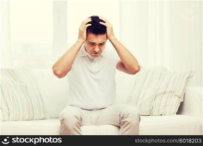 people, crisis, emotions and stress concept - unhappy man suffering from head ache at home