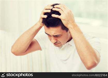 people, crisis, emotions and stress concept - unhappy man suffering from head ache at home