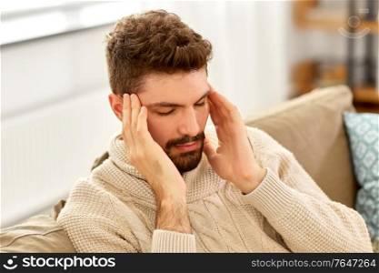 people, crisis, emotions and stress concept - unhappy man suffering from head ache at home. unhappy man suffering from head ache at home
