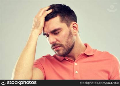 people, crisis, emotions and stress concept - unhappy man suffering from head ache over gray background. unhappy man suffering from head ache