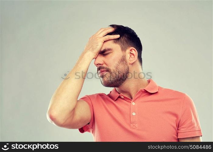 people, crisis, emotions and stress concept - unhappy man suffering from head ache over gray background. unhappy man suffering from head ache. unhappy man suffering from head ache