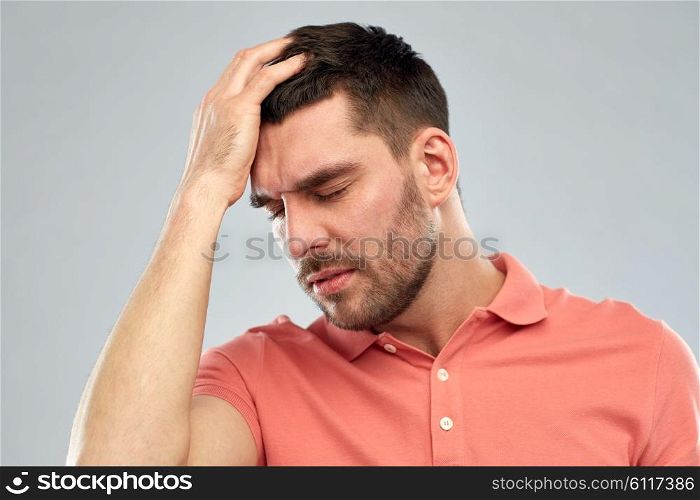 people, crisis, emotions and stress concept - unhappy man suffering from head ache over gray background