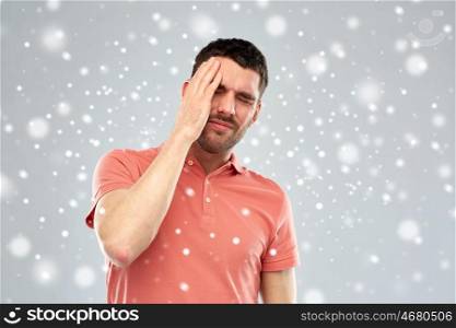 people, crisis, winter, christmas and stress concept - unhappy man suffering from head ache over snow on gray background