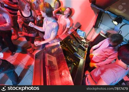 People dancing and flirting near the DJ booth at a nightclub