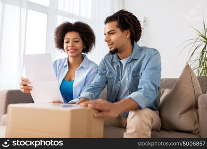 people, delivery and consumerism concept - happy couple with parcel box and paper form home. happy couple with parcel box and paper form home