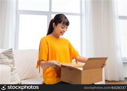 people, delivery and shipping concept - happy asian young woman with parcel box at home. happy asian young woman with parcel box at home