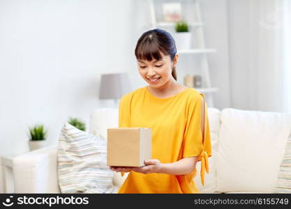 people, delivery, commerce, shipping and shopping concept - happy asian young woman with cardboard parcel box at home