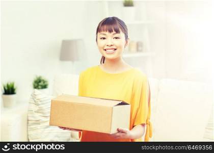 people, delivery, commerce, shipping and shopping concept - happy asian young woman with cardboard parcel box at home. happy asian young woman with parcel box at home