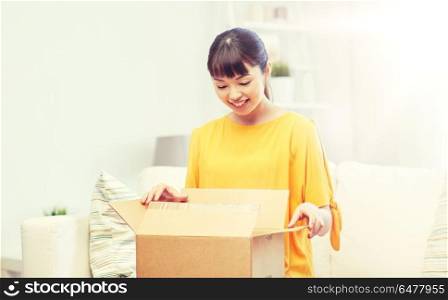 people, delivery, commerce, shipping and shopping concept - happy asian young woman with cardboard parcel box at home. happy asian young woman with parcel box at home. happy asian young woman with parcel box at home