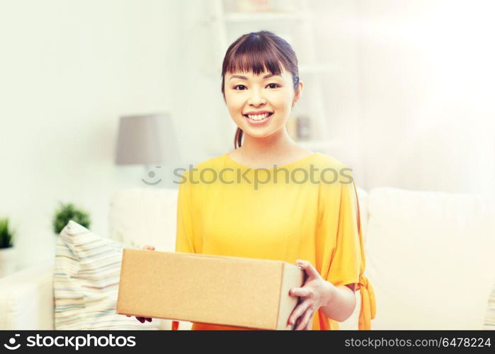 people, delivery, commerce, shipping and shopping concept - happy asian young woman with cardboard parcel box at home. happy asian young woman with parcel box at home. happy asian young woman with parcel box at home