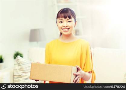 people, delivery, commerce, shipping and shopping concept - happy asian young woman with cardboard parcel box at home. happy asian young woman with parcel box at home. happy asian young woman with parcel box at home