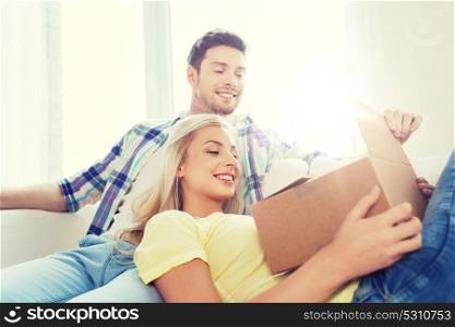 people, delivery, mail, shipping and moving concept - smiling couple with cardboard box at home. smiling couple with cardboard box at home
