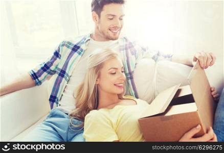 people, delivery, mail, shipping and moving concept - smiling couple with cardboard box at home. smiling couple with cardboard box at home