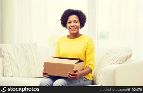 people, delivery, shipping and postal service concept - happy african american young woman holding open cardboard box or parcel at home