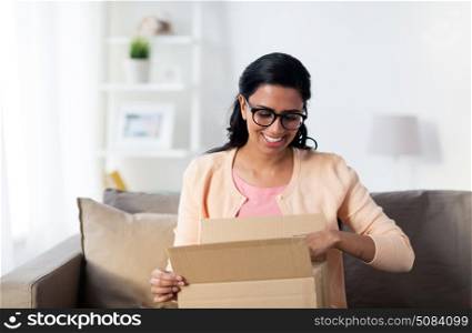 people, delivery, shipping and postal service concept - happy young indian woman holding open cardboard box or parcel at home. happy young indian woman with parcel box at home. happy young indian woman with parcel box at home