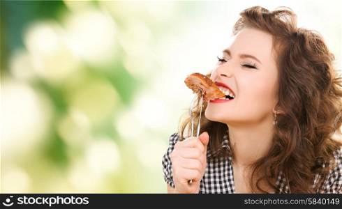 people, diet and food concept - hungry young woman eating meat on fork over green natural background