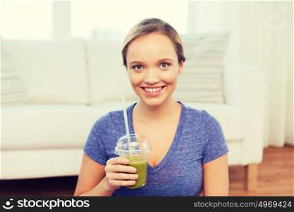people, diet and healthy lifestyle concept - happy woman with cup of smoothie sitting on mat at home. happy woman with smoothie sitting on mat at home
