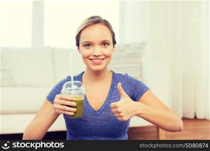 people, diet and healthy lifestyle concept - happy woman with cup of smoothie at home and showing thumbs up. happy woman with cup of smoothie showing thumbs up