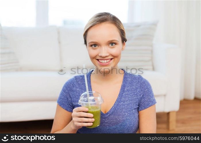 people, diet and healthy lifestyle concept - happy woman with cup of smoothie sitting on mat at home