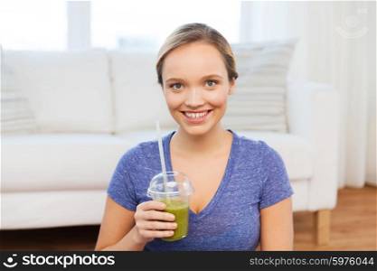 people, diet and healthy lifestyle concept - happy woman with cup of smoothie sitting on mat at home