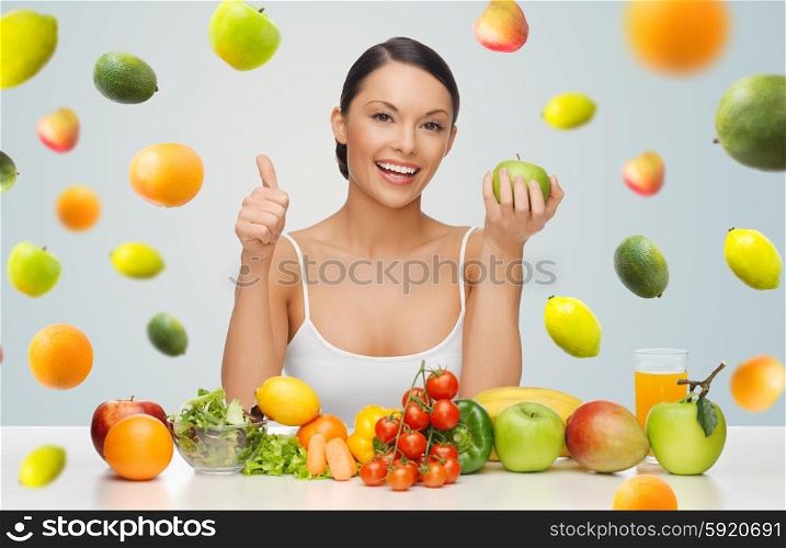 people, diet, gesture and vegetarian concept- happy asian woman with healthy food showing thumbs up over gray background with falling fruits