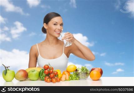 people, diet, healthy eating and food concept - happy woman drinking water from glass, fruits and vegetables over blue sky and clouds background. happy woman with glass of water and healthy food