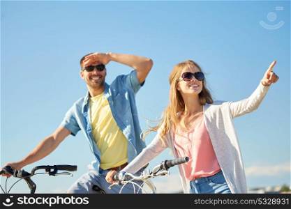 people, direction and lifestyle concept - happy young couple with bicycles at country in summer. happy young couple with bicycles outdoors