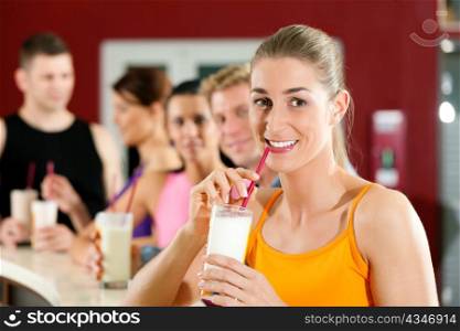 People drinking protein shake after workout in gym or fitness club