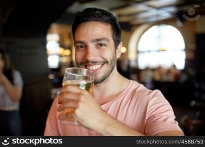 people, drinks, alcohol and leisure concept - close up of happy young man drinking beer at bar or pub