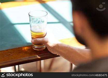 people, drinks, alcohol and leisure concept - close up of man drinking beer from glass at bar or pub