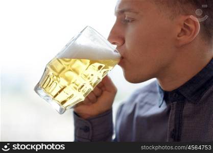 people, drinks, alcohol and leisure concept - close up of young man drinking beer from glass mug