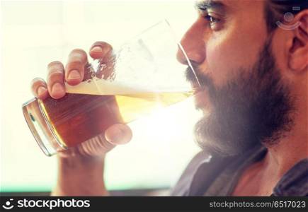 people, drinks, alcohol and leisure concept - close up of young man drinking beer from glass at bar or pub. close up of man drinking beer at bar or pub. close up of man drinking beer at bar or pub