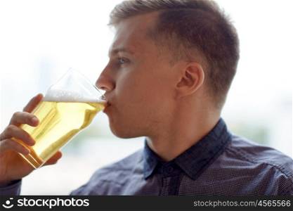 people, drinks, alcohol and leisure concept - close up of young man drinking beer from glass