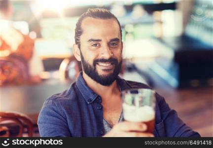 people, drinks, alcohol and leisure concept - happy young man drinking beer at bar or pub. happy man drinking beer at bar or pub. happy man drinking beer at bar or pub