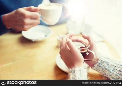 people, drinks and dating concept - close up of couple drinking tea at cafe. close up of couple drinking tea at cafe