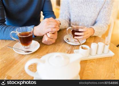 people, drinks and dating concept - close up of couple drinking tea at cafe