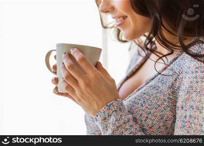 people, drinks and leisure concept - close up of happy young woman with cup of tea or coffee at home