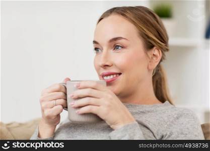 people, drinks and leisure concept - happy woman with cup of tea or coffee drinking at home. happy woman with cup or mug drinking at home